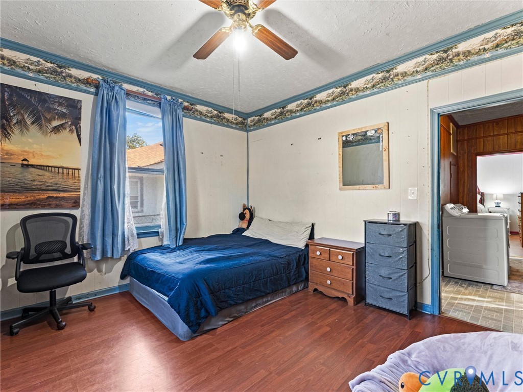 Bedroom featuring wood-finish flooring, a central ceiling fan with integrated lighting, and decorative wall border trim