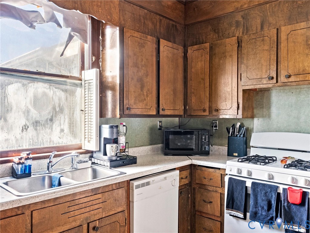Kitchen featuring wood cabinetry, double-basin stainless steel sink with high-arc faucet, and light-toned countertops