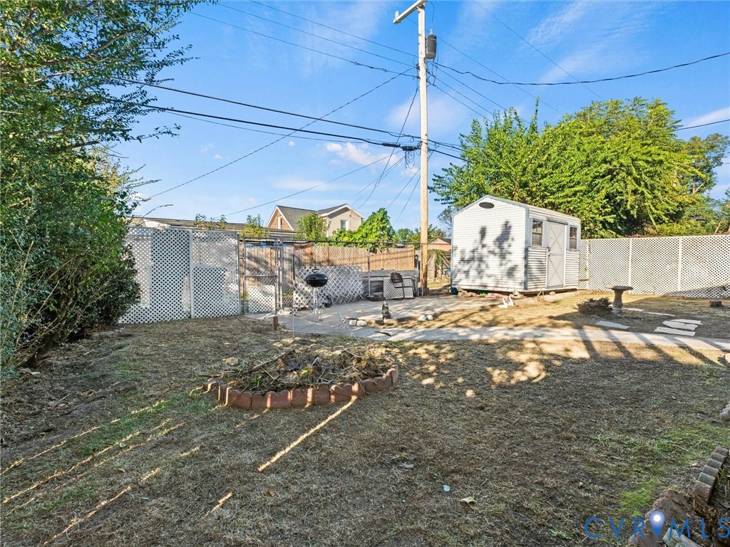 Backyard featuring a detached storage shed, privacy fencing, and masonry garden edging