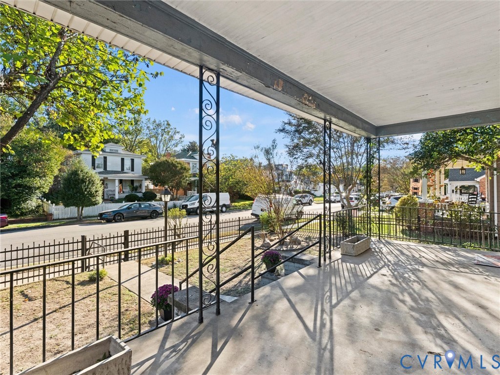 Covered porch featuring concrete flooring, decorative wrought-iron support columns, and wrought-iron railings