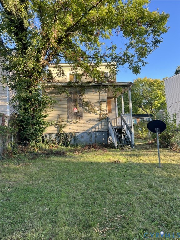 Exterior of a multi-story residence featuring horizontal siding, a covered porch with wooden stairs, and a level yard with mature trees Exterior of a multi-story residence featuring horizontal siding, a covered porch with wooden stairs, and a level yard with mature trees