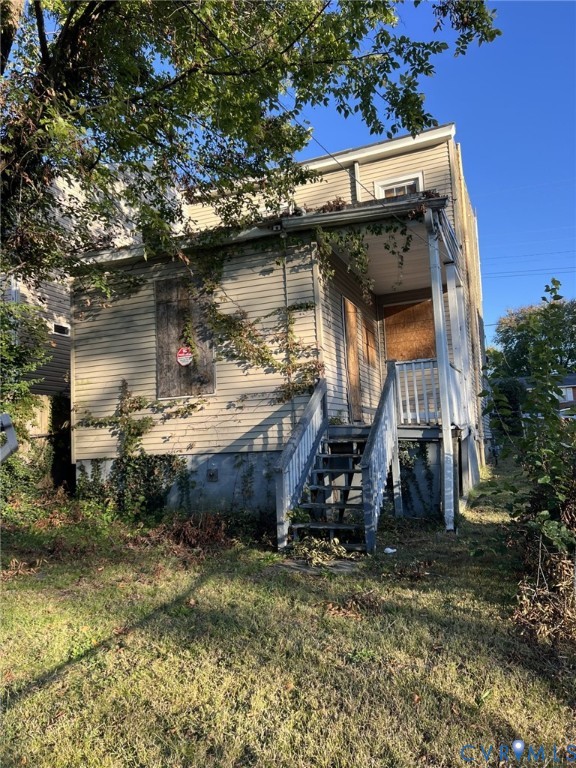 Two-story exterior featuring light-colored horizontal siding, a covered porch with wooden stairs, and a concrete foundation Two-story exterior featuring light-colored horizontal siding, a covered porch with wooden stairs, and a concrete foundation