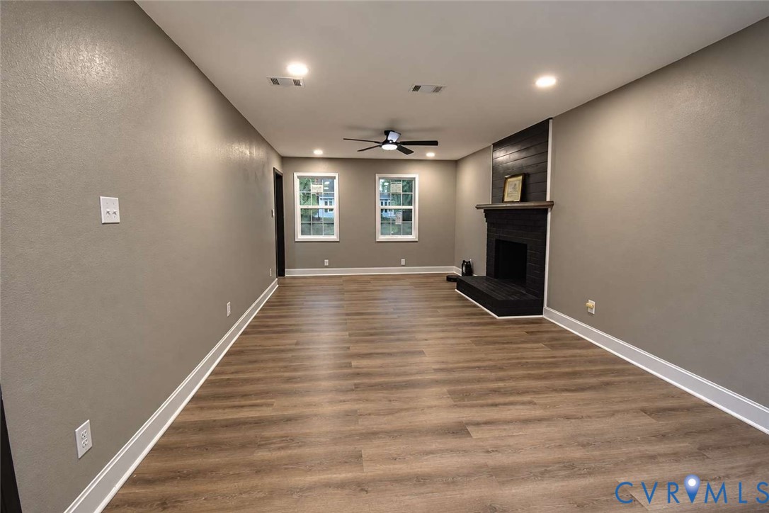 Wood-finish flooring, recessed lighting, ceiling fan, and a painted brick fireplace with a wood mantel