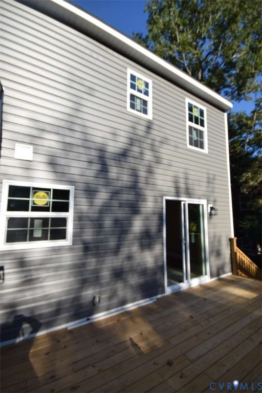 Two-story exterior with horizontal siding, wooden deck, glass sliding patio door, and multi-pane windows