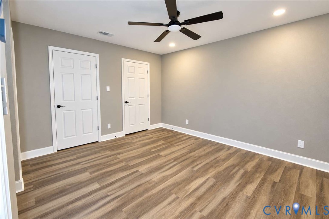 Neutral-toned interior featuring wood-finish flooring, a contemporary ceiling fan with integrated lighting, recessed lighting, and six-panel doors with matte black hardware