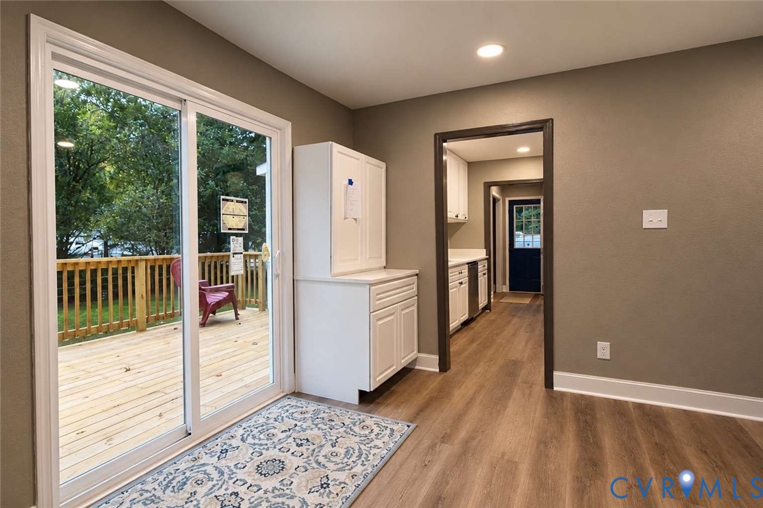 Wood-finish flooring, sliding glass patio door, white built-in cabinetry, and access to an outdoor deck