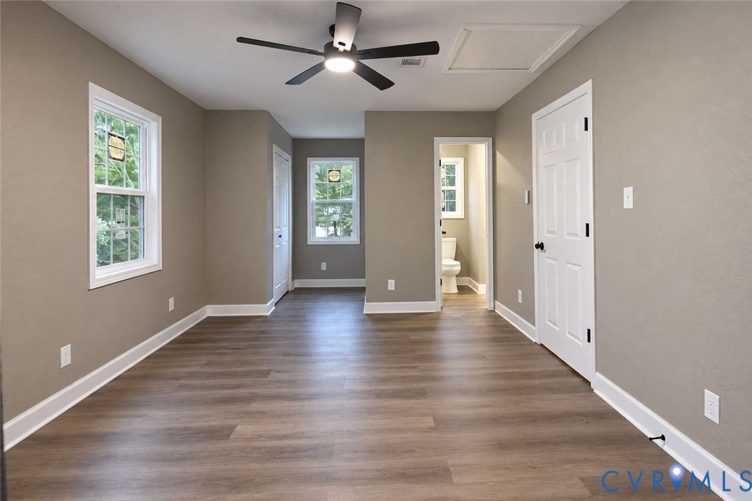 Neutral-toned interior featuring wood-finish flooring, multi-pane windows, and a matte black ceiling fan with integrated lighting