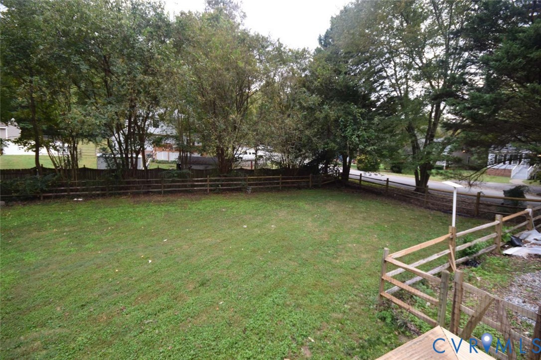 Expansive backyard featuring a level lawn, mature trees, and split-rail perimeter fencing