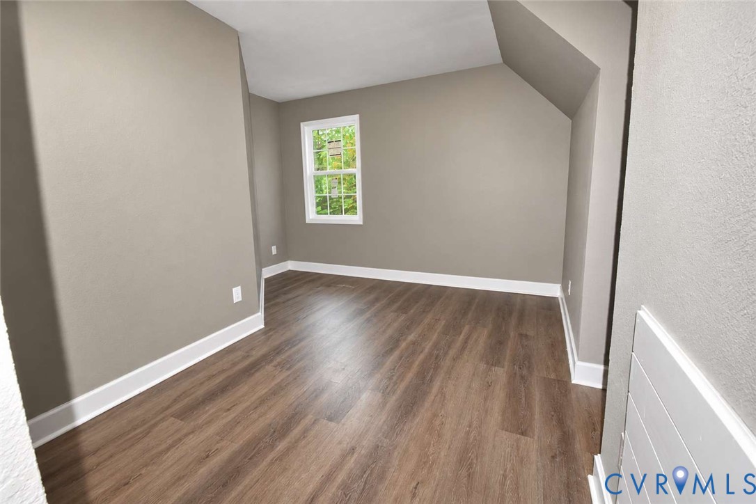 Neutral-toned walls, wood-finish flooring, and a single-hung window with exterior greenery