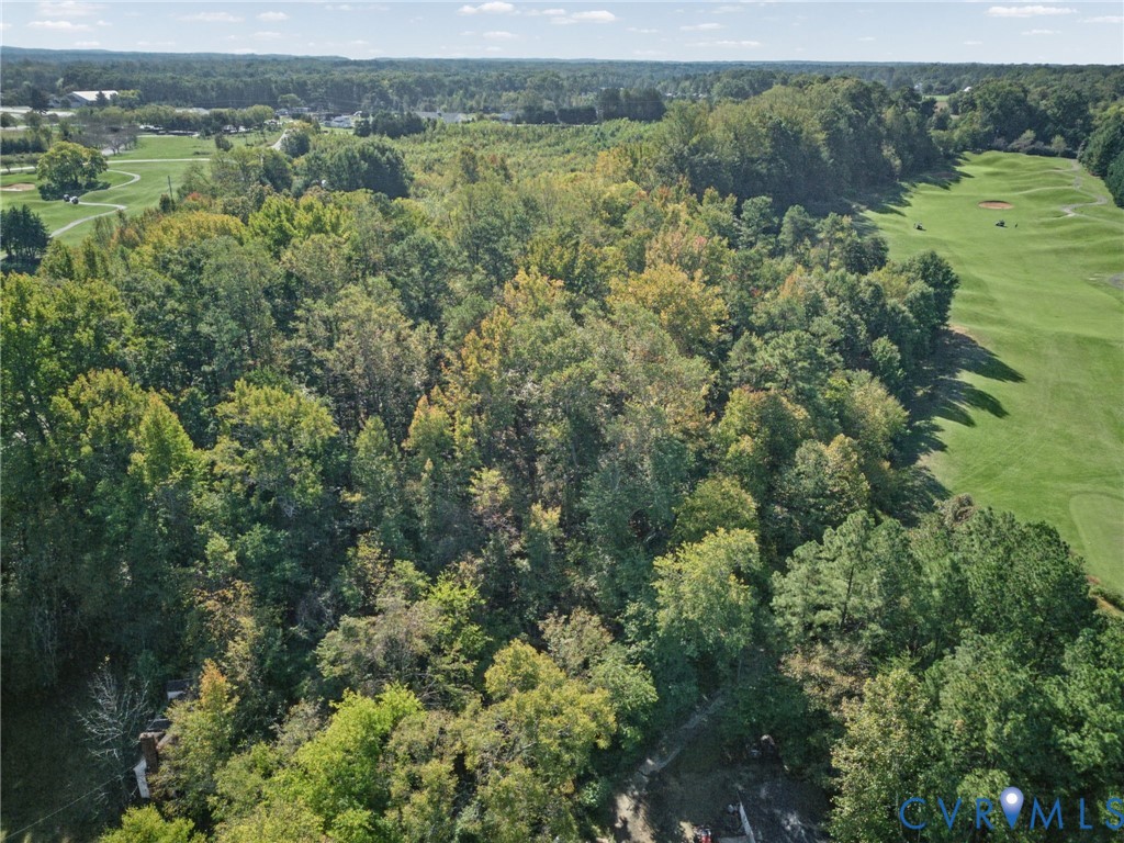 Expansive lot featuring mature deciduous and coniferous trees, dense woodland foliage, and direct proximity to manicured course grounds