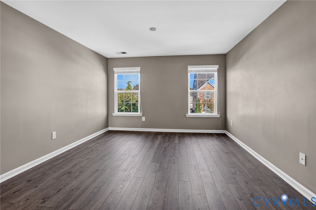Interior space featuring wood-finish flooring, neutral wall tones, and two double-hung windows with grid detailing