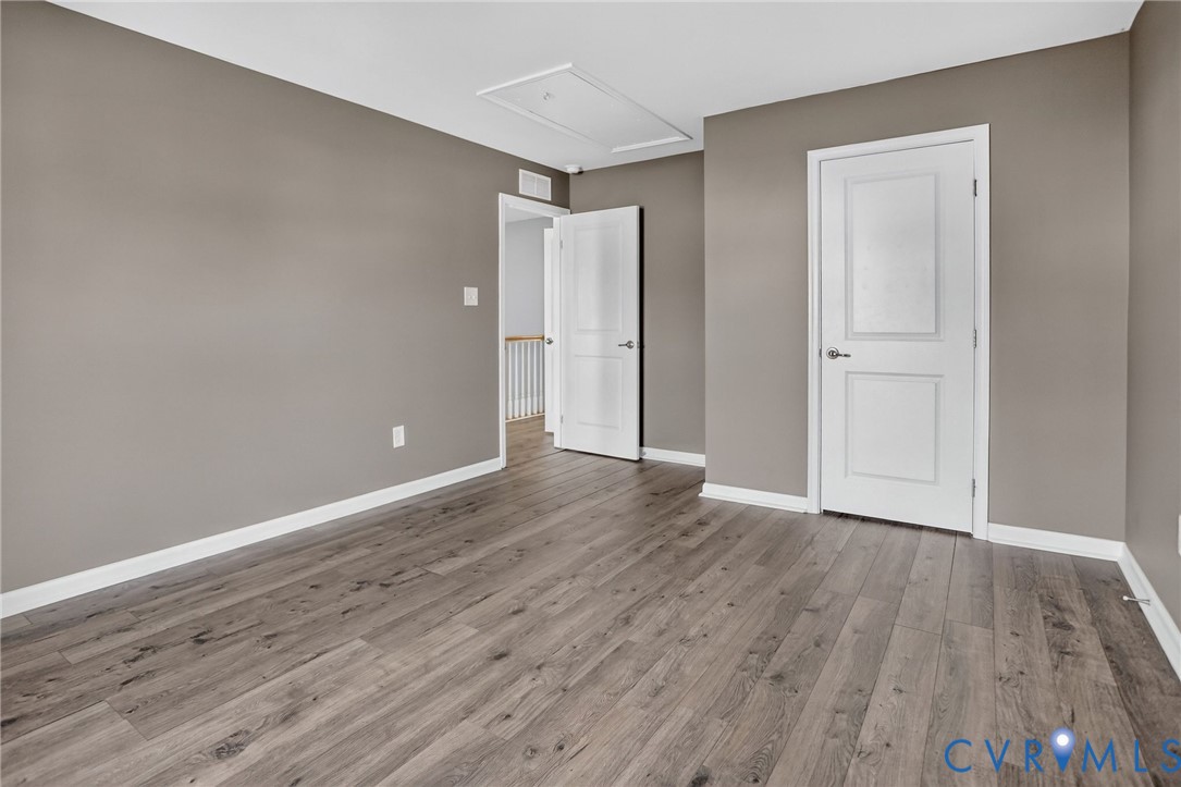 Neutral-toned walls paired with wood-finish flooring, featuring two-panel interior doors and a ceiling access panel