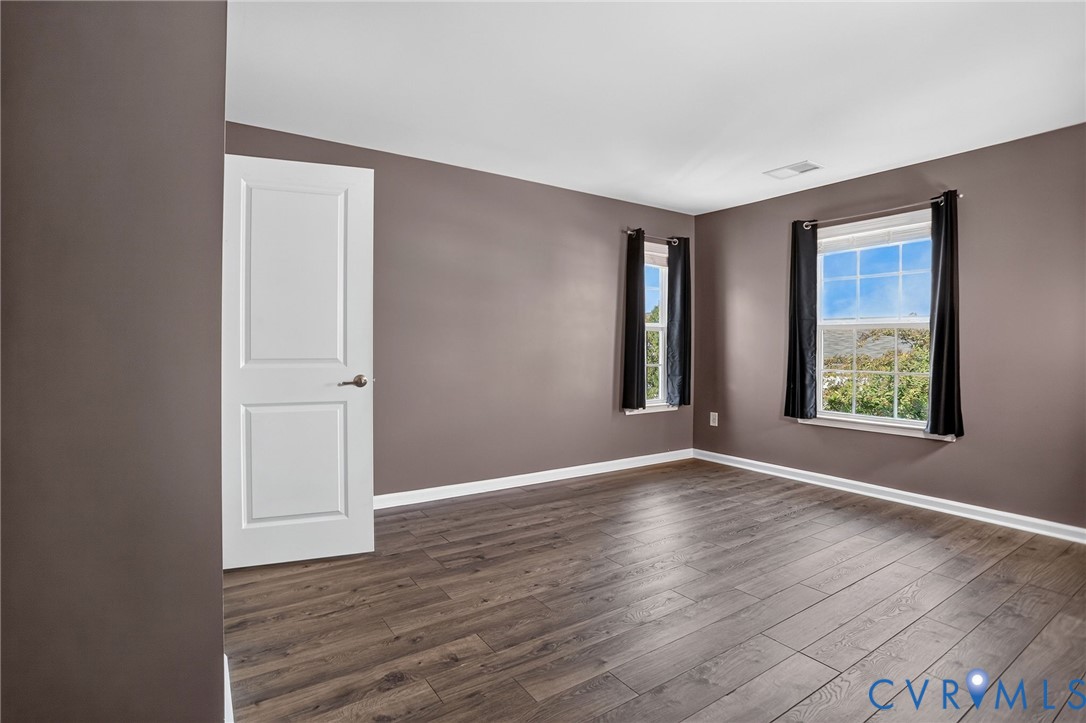 Wood-finish flooring, two double-hung windows with muntin detailing, and a solid-core interior door