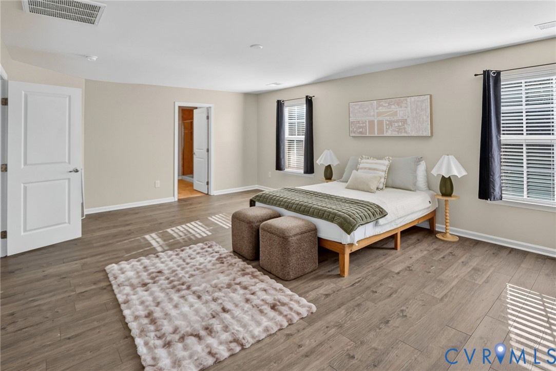 Spacious room featuring wood-finish flooring, neutral wall paint, and dual windows