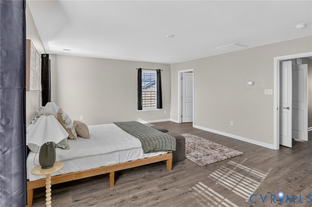 Spacious room featuring tray ceiling, wood-finish flooring, and multi-panel interior doors