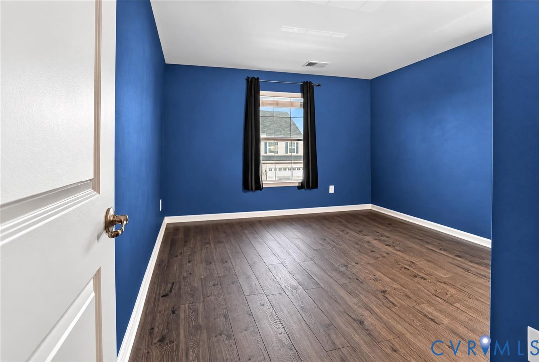 Room featuring wood-finish flooring, a single window, and a white six-panel interior door with a metallic knob