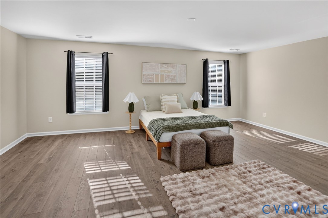 Spacious room featuring wood-finish flooring, neutral wall paint, and dual windows with grid detailing