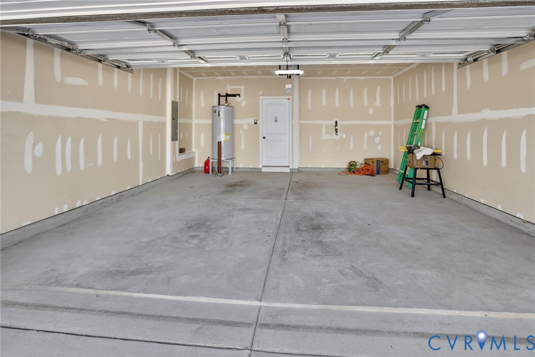 Attached two-car garage featuring a concrete floor, sectional roll-up door, interior access door, and water heater