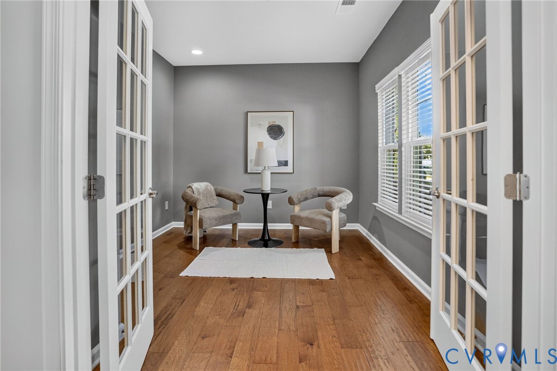 Room featuring wood-finish flooring, white French doors with glass panes, and recessed lighting Room featuring wood-finish flooring, white French doors with glass panes, and recessed lighting