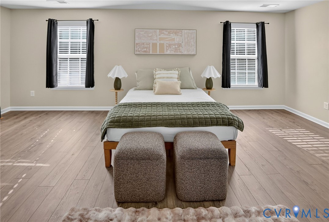 Wood-finish flooring, neutral wall tones, and dual windows with window treatments