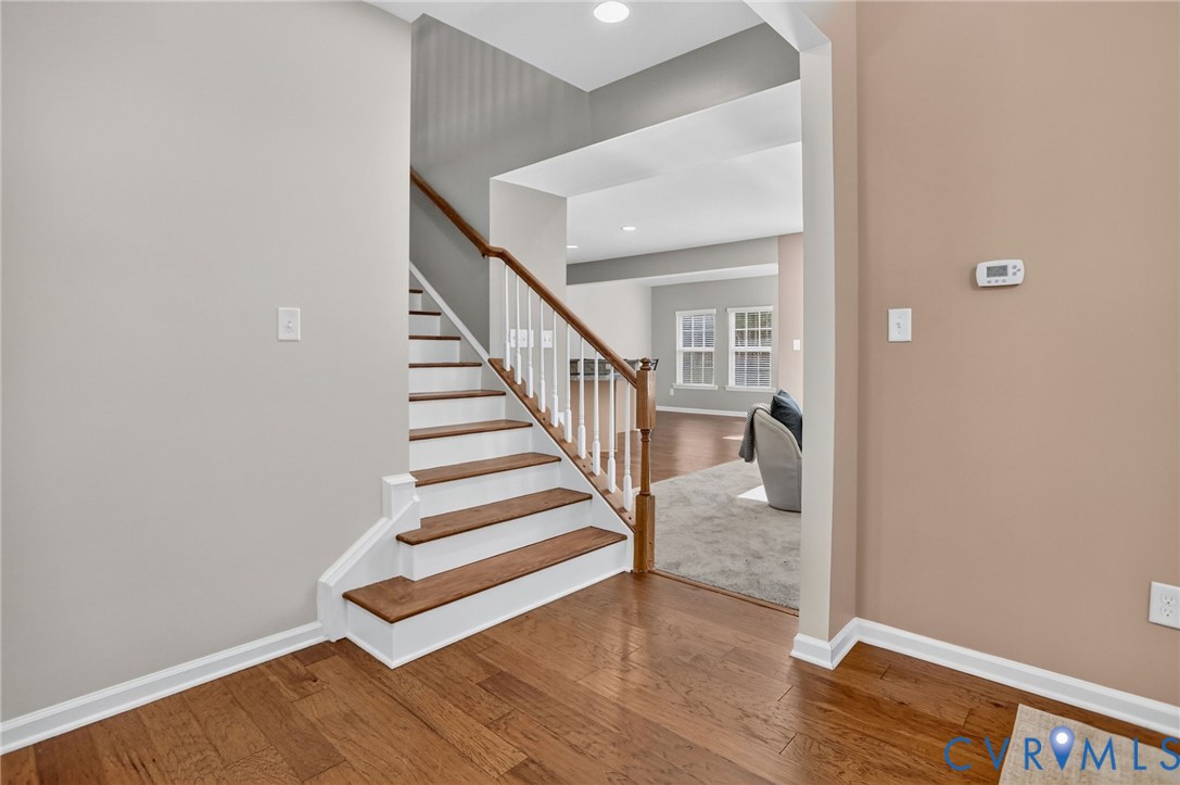 Staircase featuring wood-finish treads, white risers, and a wooden handrail with white balusters, complemented by wood-finish flooring and recessed lighting Staircase featuring wood-finish treads, white risers, and a wooden handrail with white balusters, complemented by wood-finish flooring and recessed lighting