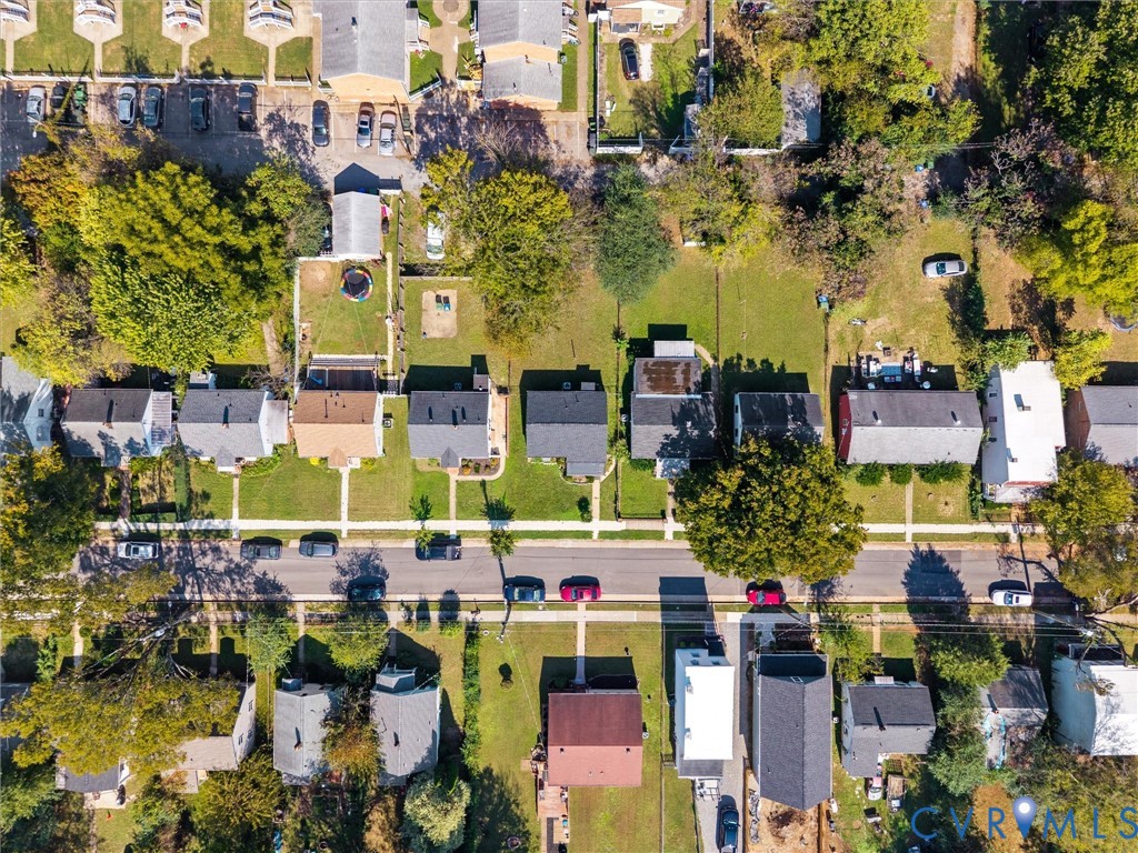 Aerial perspective of a suburban neighborhood featuring tree-lined streets, defined lot lines, varied architectural styles, and consistent sidewalk placement