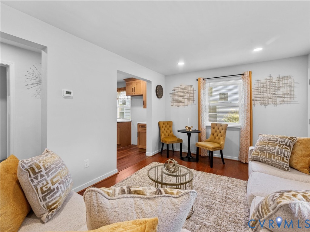 Living area featuring wood-finish flooring, recessed lighting, and a window with casing