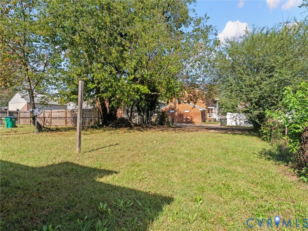 Expansive backyard featuring mature trees, a wood-post fence, and a level lawn