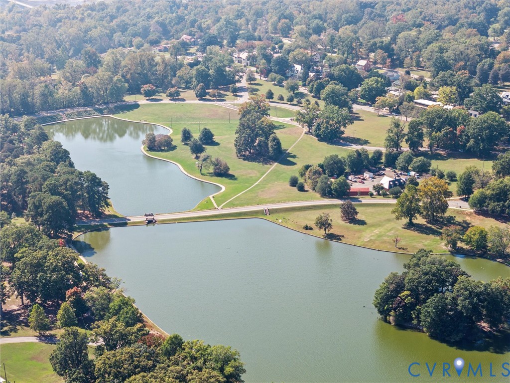 Aerial view of multi-acre grounds featuring dual ponds, mature woodland canopy, expansive open lawn spaces, and winding paved paths