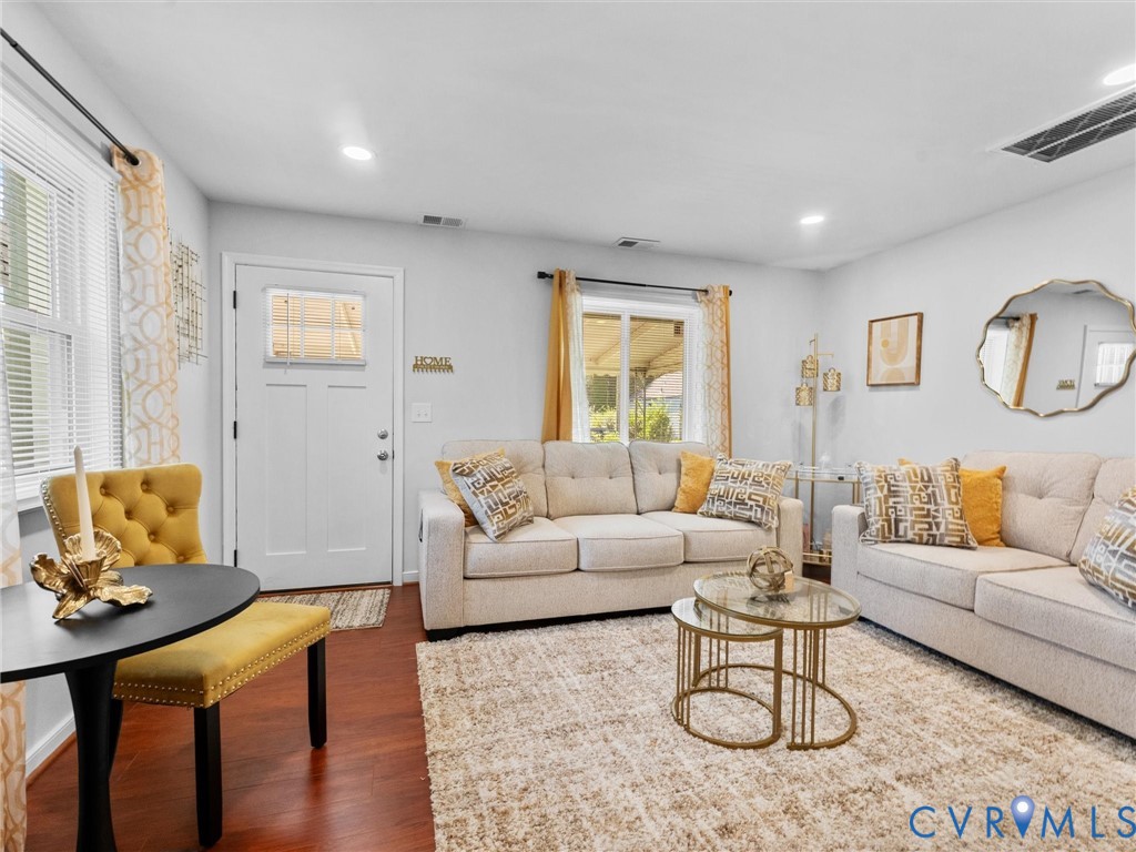 Living area featuring wood-finish flooring, white-painted walls, and a single-light entry door