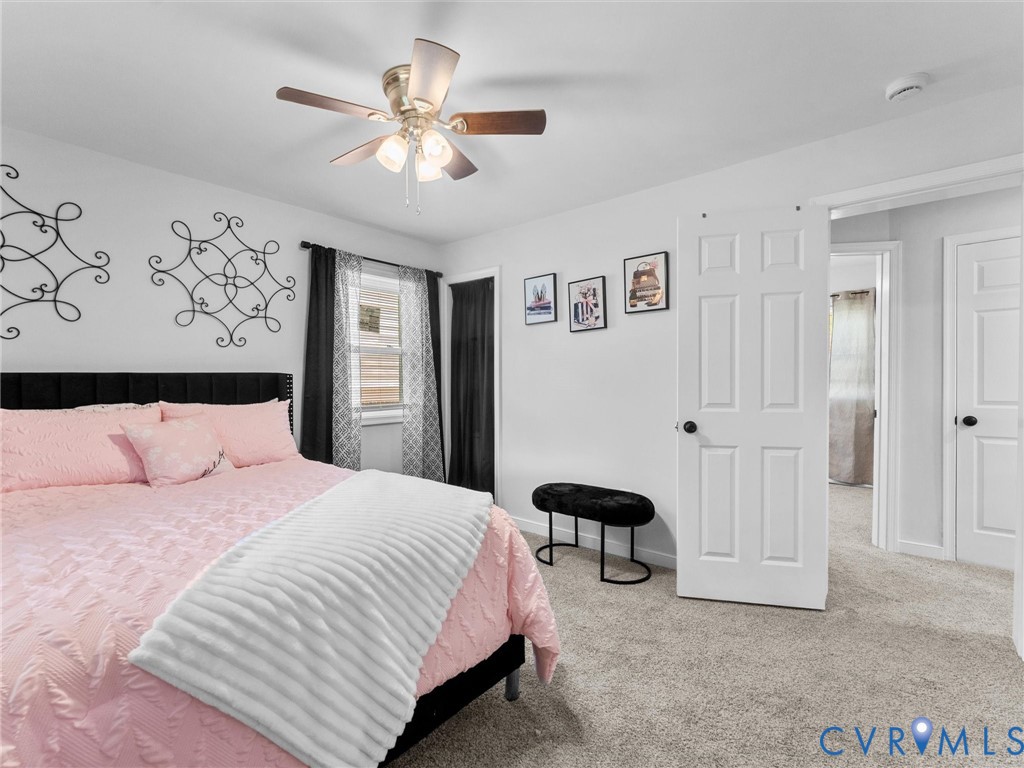 Room featuring plush carpeting, a central ceiling fan with multi-light fixture, and two panel-style interior doors