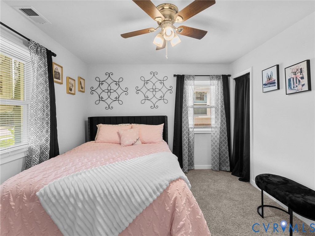 Neutral wall finishes, plush carpeting, ceiling fan with integrated lighting, and dual windows with wide-slat blinds