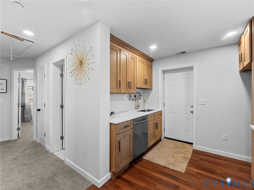 Kitchenette featuring wood cabinetry, white countertops, an undermount stainless steel sink, a stainless steel dishwasher, and recessed lighting