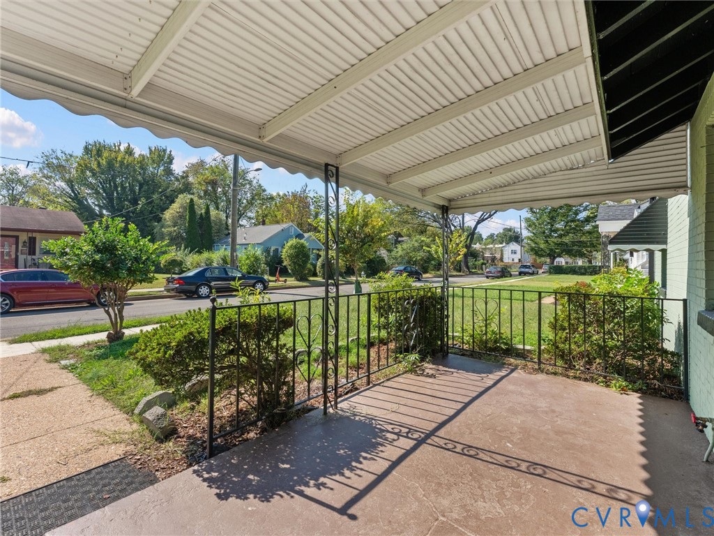 Covered front porch featuring concrete flooring and decorative wrought-iron railings