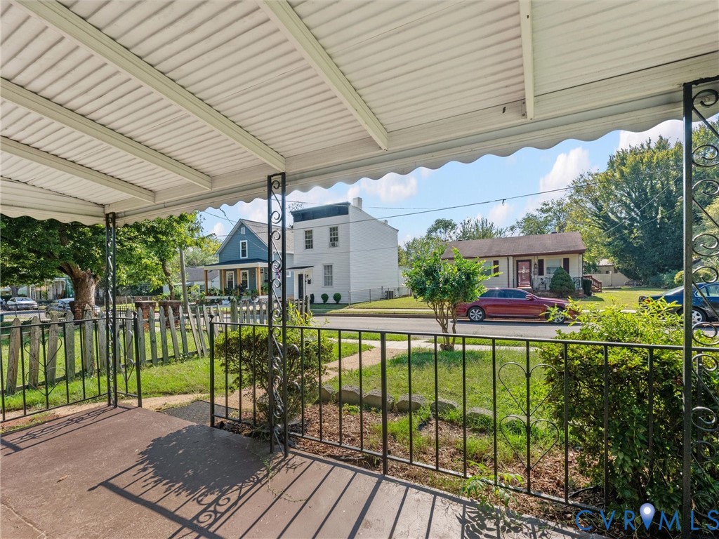 Covered front porch featuring a concrete floor, decorative metal railings, and a metal roof canopy