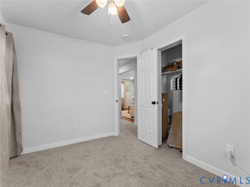 Neutral-toned carpeted flooring, white interior walls, ceiling fan with integrated lighting, and a six-panel closet door