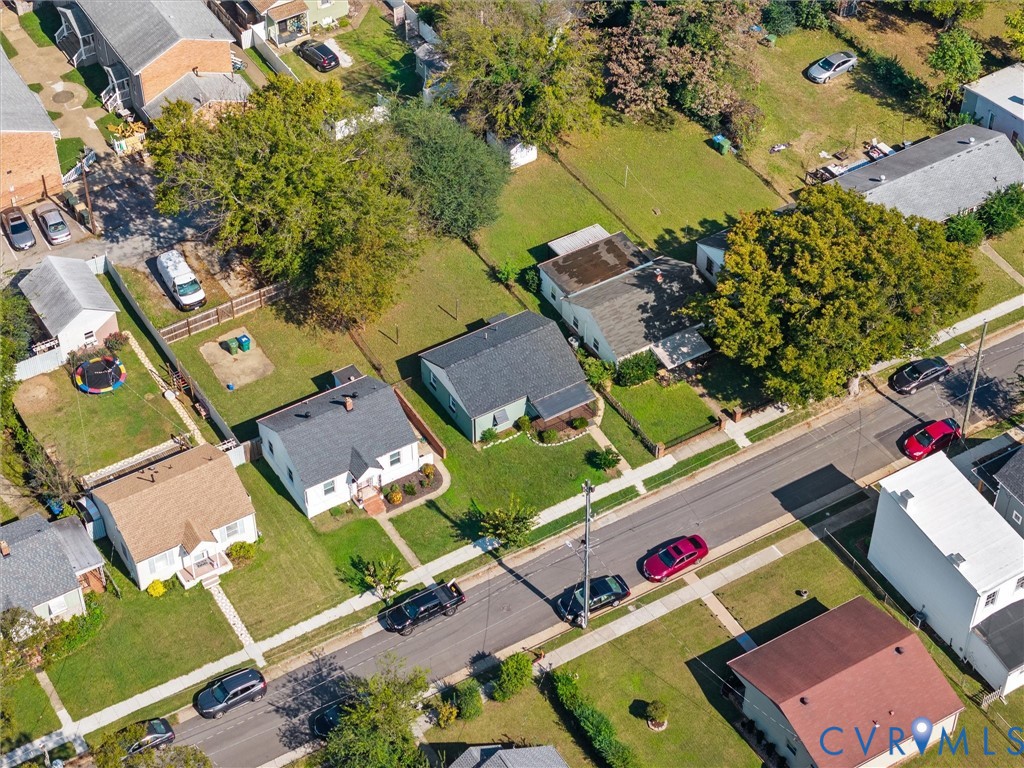 Aerial perspective of suburban residential lots featuring mature trees, expansive lawns, paved street access, and sidewalk infrastructure