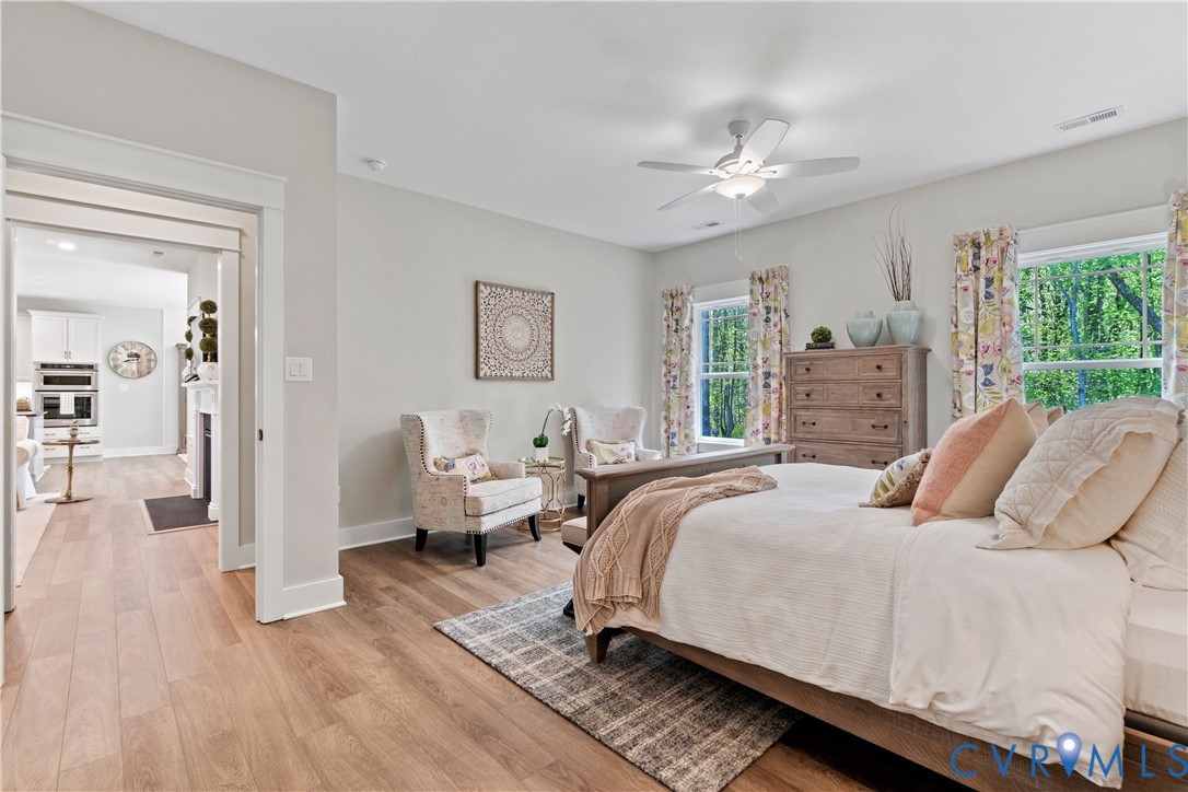 Neutral-toned interior featuring wood-finish flooring, multi-pane windows, and a ceiling-mounted light fixture with integrated fan