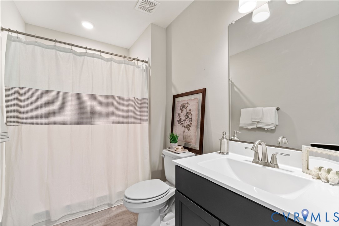 Bathroom featuring a dark-toned vanity, white countertop with integrated sink, brushed-nickel faucet, and a large frameless mirror