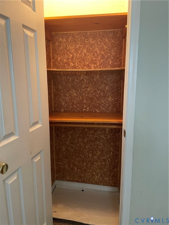 Storage closet featuring a six-panel door, built-in shelving, and a hanging rod