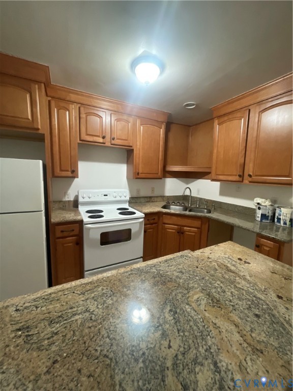 Kitchen featuring wood cabinetry, stone countertops, breakfast bar, dual-basin stainless steel sink, and white electric range