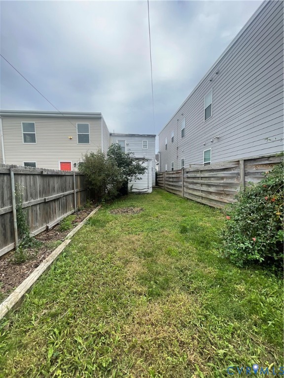 Fenced backyard featuring a manicured lawn, established landscaping, and timber border edging