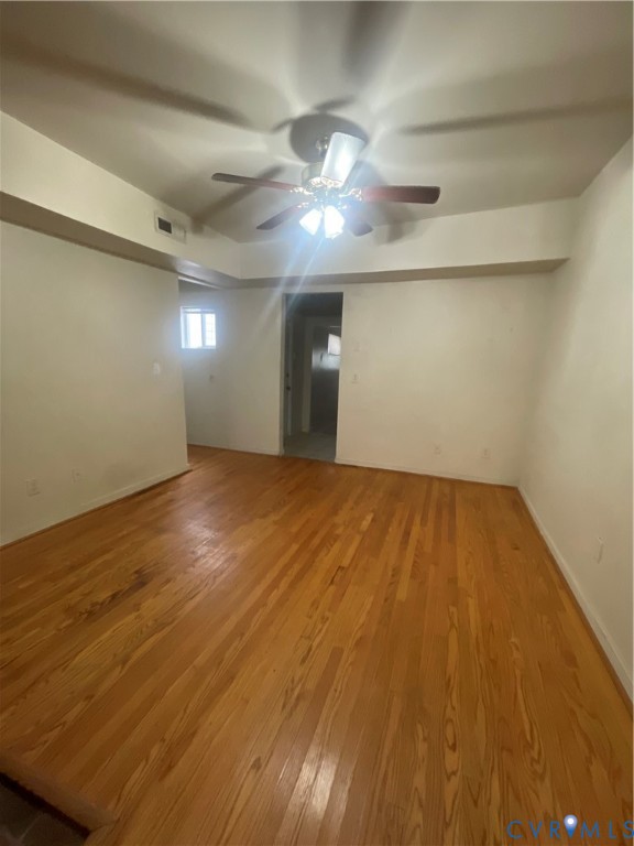 Interior space featuring wood-finish flooring, recessed ceiling detailing, and a central ceiling fan with integrated lighting