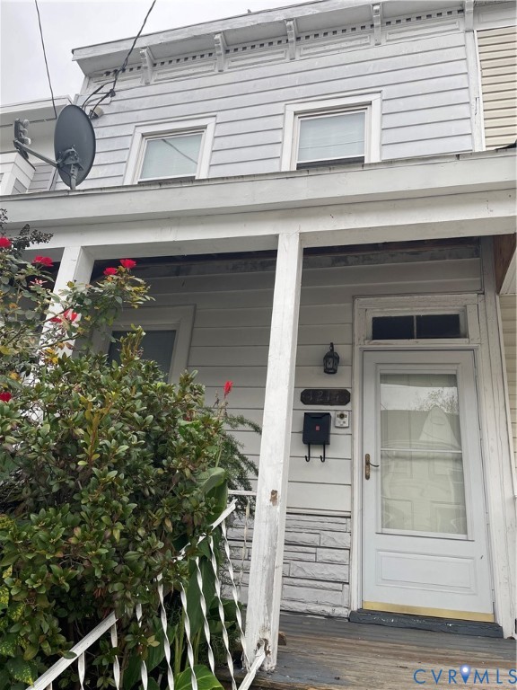 Exterior facade featuring horizontal siding, a covered front porch with decorative iron railings, stone masonry accents, and a transom window above the entry door Exterior facade featuring horizontal siding, a covered front porch with decorative iron railings, stone masonry accents, and a transom window above the entry door