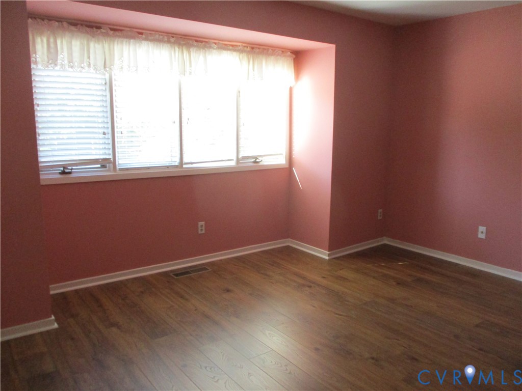 Interior space featuring wood-finish flooring and a multi-panel window configuration with a recessed alcove