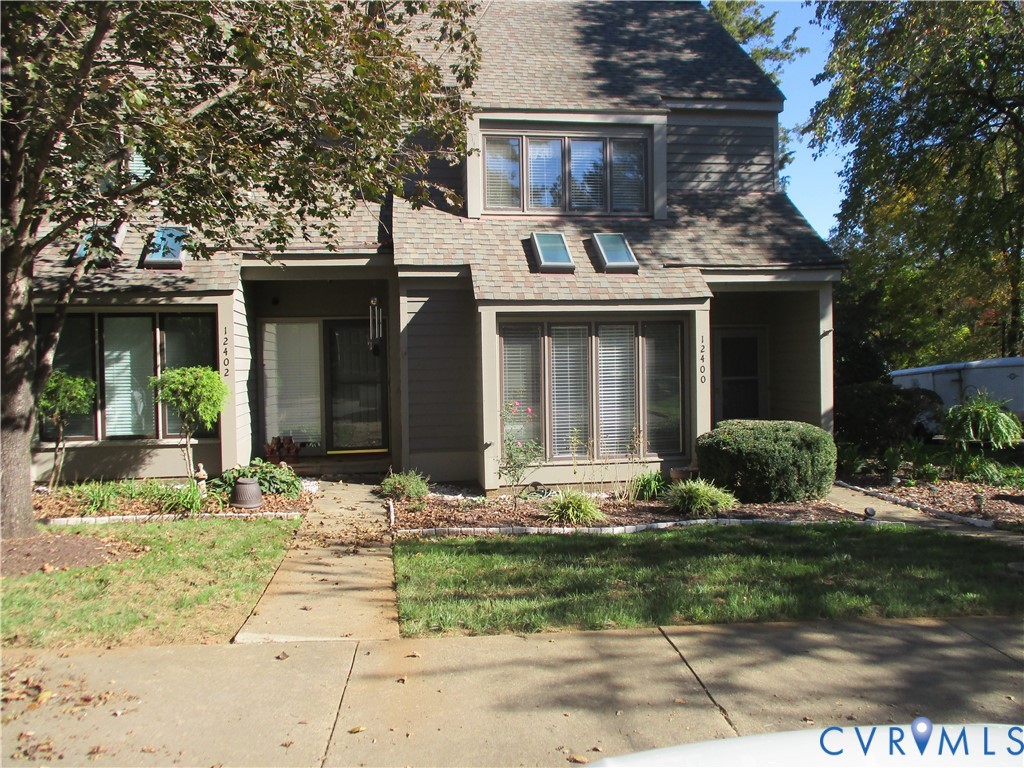 Multi-level exterior featuring wood-style siding, roof skylights, bay windows, and a concrete driveway