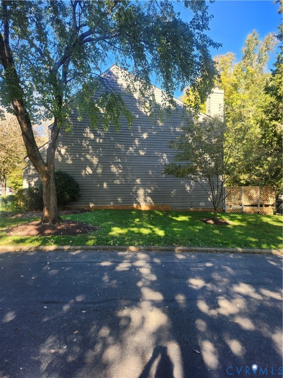 Side profile of home featuring horizontal siding, exterior chimney, and latticed privacy screen