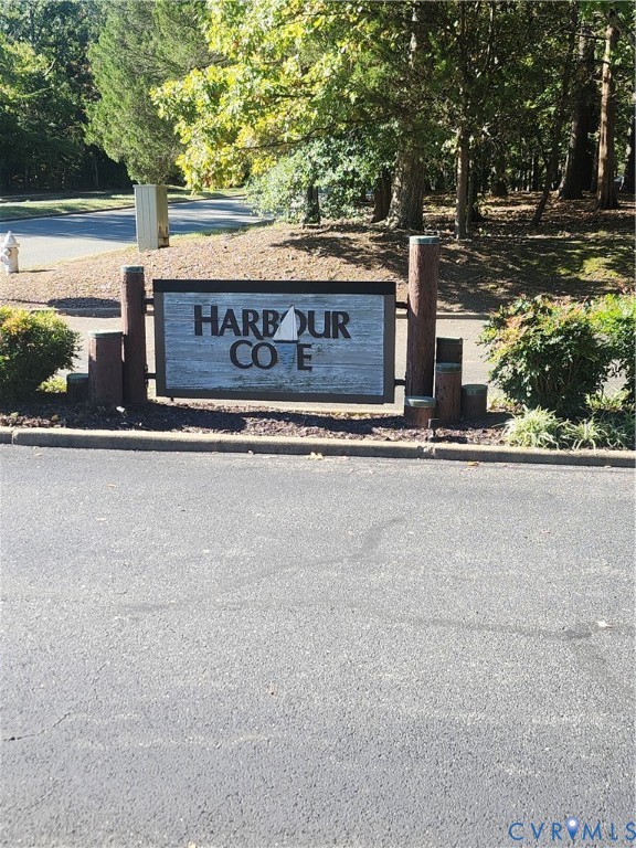 Community monument sign featuring rustic wood-finish posts and textured paneling surrounded by mature landscaping
