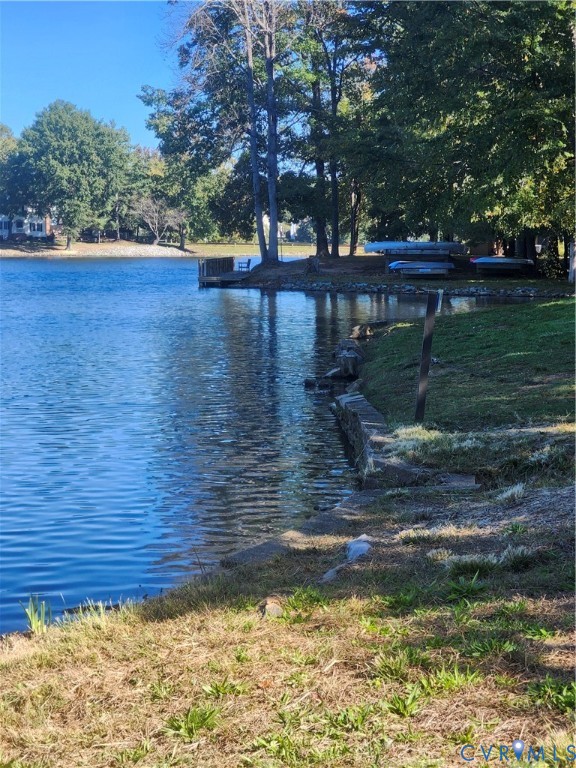 Waterfront property featuring a stone bulkhead, wooden dock, mature trees, and expansive shoreline
