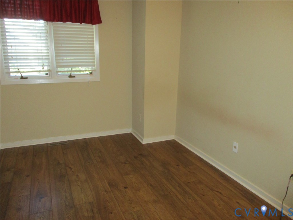 Interior room featuring wood-finish flooring and double-hung window with horizontal blinds